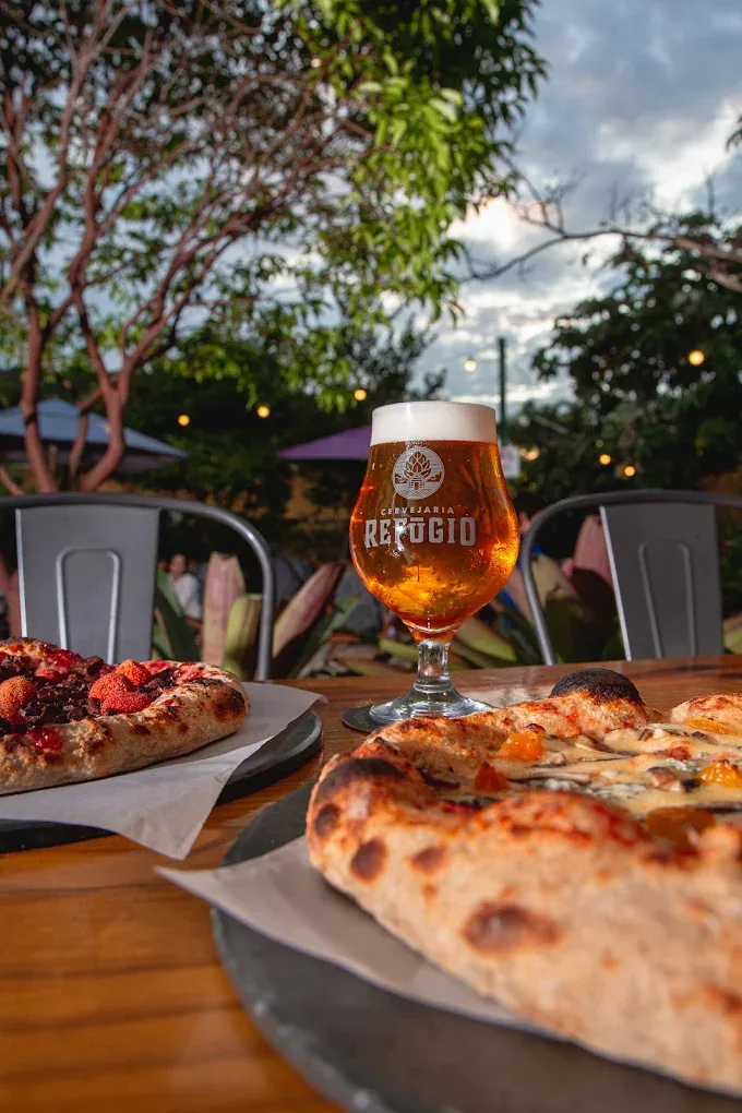 Chopp e pizza no jardim da Cervejaria Refúgio ao entardecer